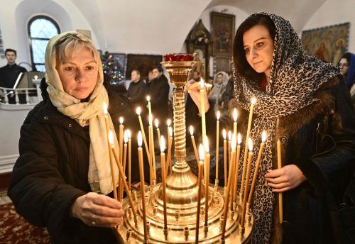 Frauen entzünden während des Weihnachtsgottesdienstes in einer Kirche der orthodoxen Kirche der Ukraine in Kiew Kerzen. AFP