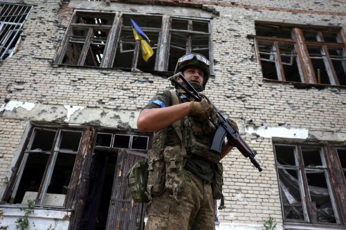 Ein ukrainischer Soldat steht vor einem schwer beschädigten Kulturzentrum im kürzlich befreiten Dorf Blahodatne. AFP