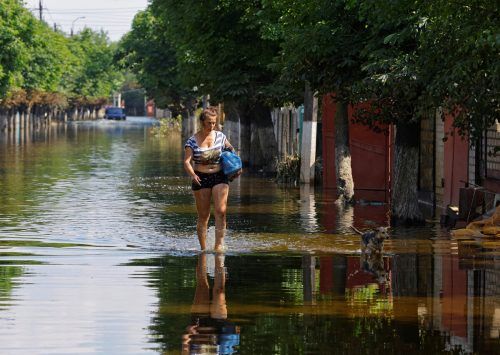 Eine Frau läuft eine überflutete Straße im russisch besetzten Gebiet entlang. Reuters