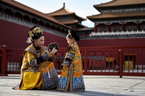 Eine Frau und ein Mädchen in traditioneller Tracht unterhalten sich während einer Fotosession bei der Verbotenen Stadt in Peking. AFP