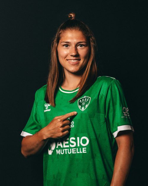 Sarah Klotz zeigt voller Stolz auf das Klubemblem auf dem Trikot.