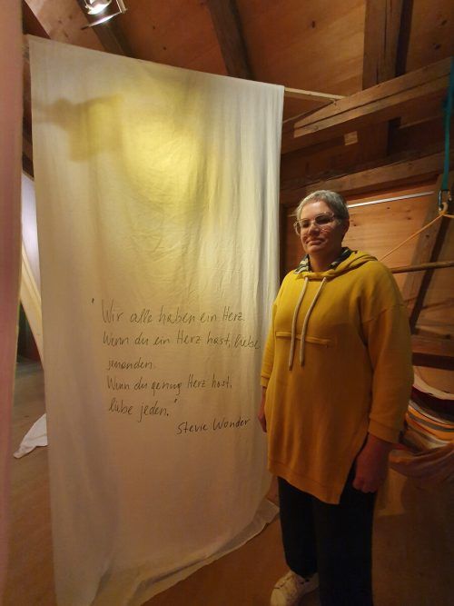 Birgit Fiel vor einem der Spruchbahnen mit einem Stevie-Wonder-Zitat. Schiretz