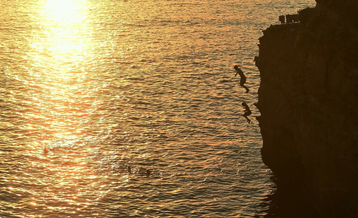 An einem heißen Tag springen Menschen in der Nähe des Rocher de la Vierge in Biarritz im Südwesten Frankreichs ins Wasser. AFP
