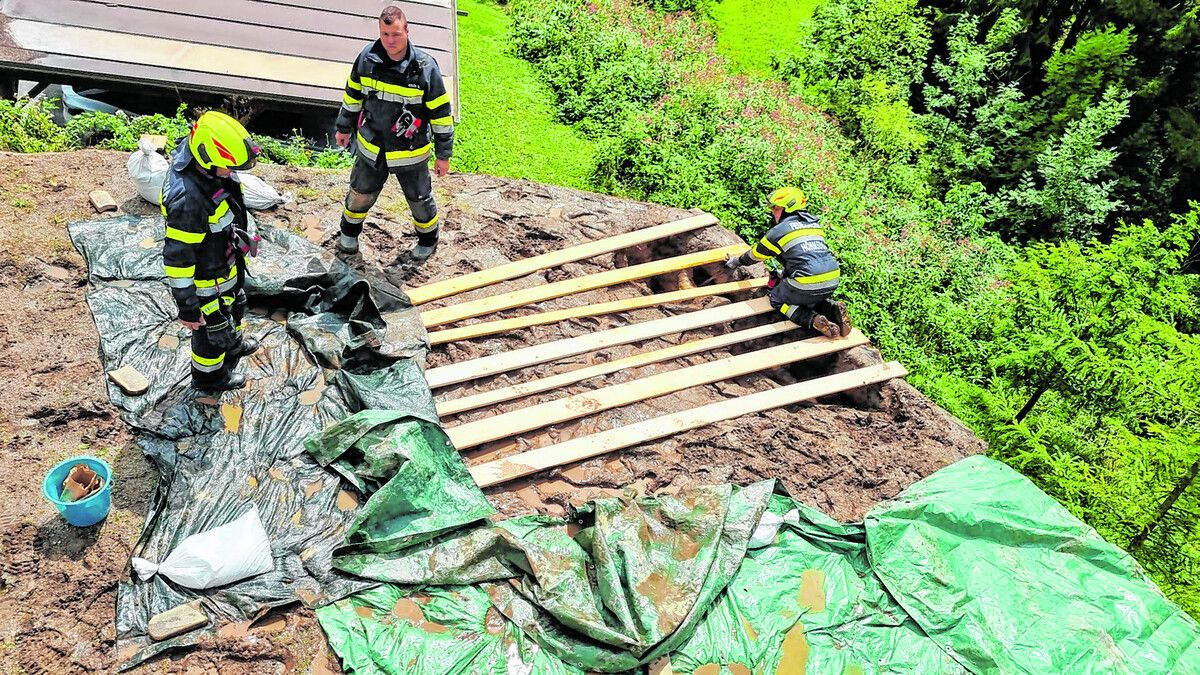 Aufgeweichte Hänge werden von Feuerwehrleuten stabilisiert. apa