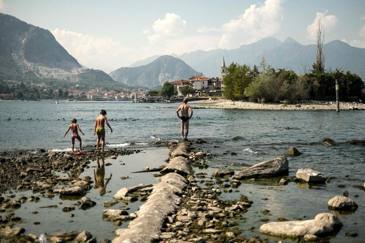 Badende laufen zwischen Isola Bella und Scoglio della Malgera in Stresa am Lago Maggiore auf Felsen. Der Wasserstand ist aktuell niedrig. AFP