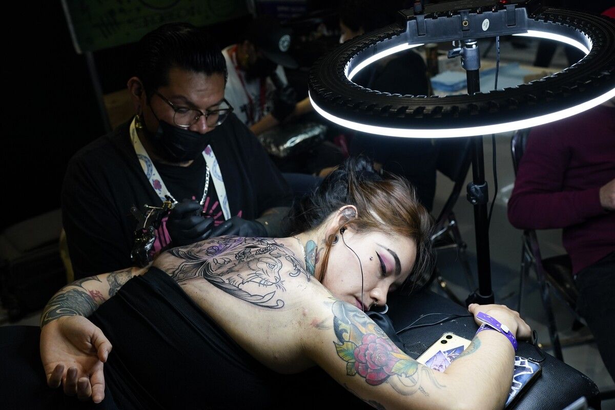 Bei einer Tattoo-Convention in Mexiko-Stadt arbeitet ein Tätowierer auf dem Rücken einer Frau. AP