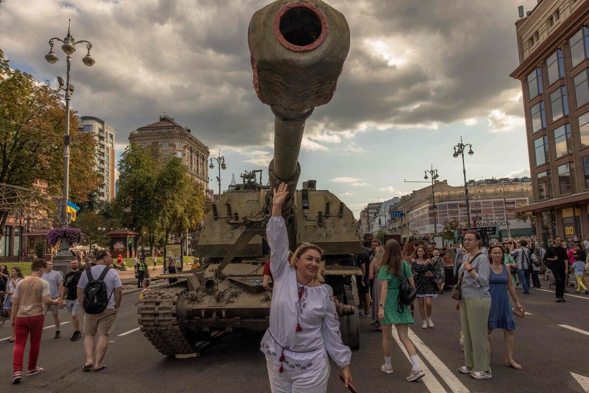Zum Unabhängigkeitstag posiert diese Frau vor einem zerstörten russischen Panzer, der in der ukrainischen Hauptstadt Kiew präsentiert wird. AFP