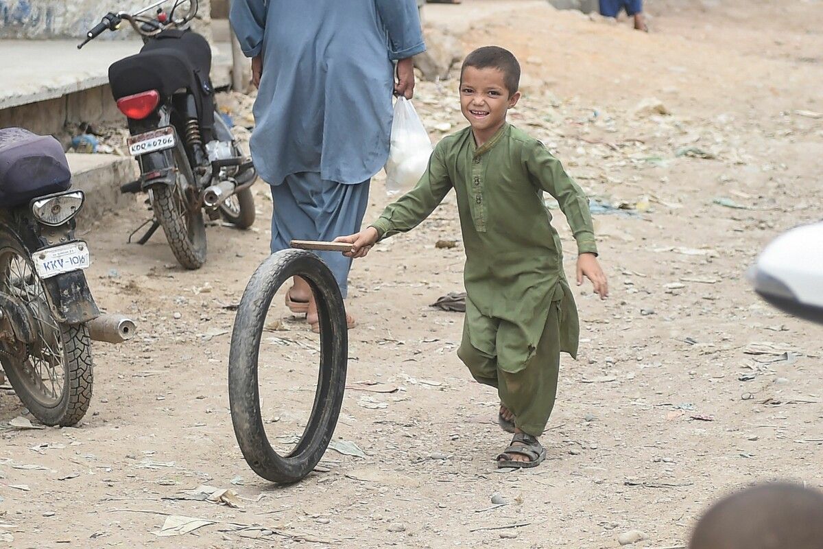 Ein Junge spielt in einem afghanischen Flüchtlingslager in Karatchi in Pakistan mit einem Reifen. AFP