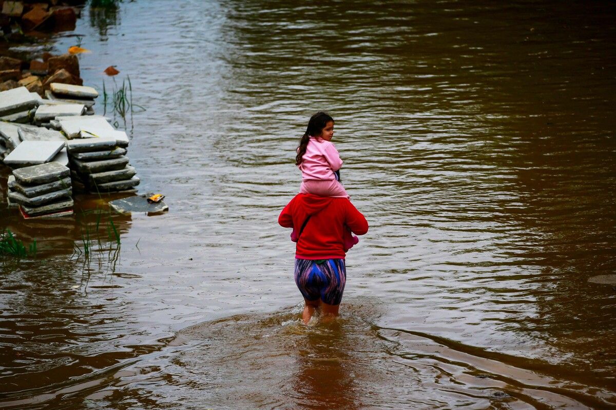 Mit einem Kind auf den Schultern kämpft sich diese Bewohnerin von Porto Alegre, Brasilien, über eine überflutete Straße. AFP