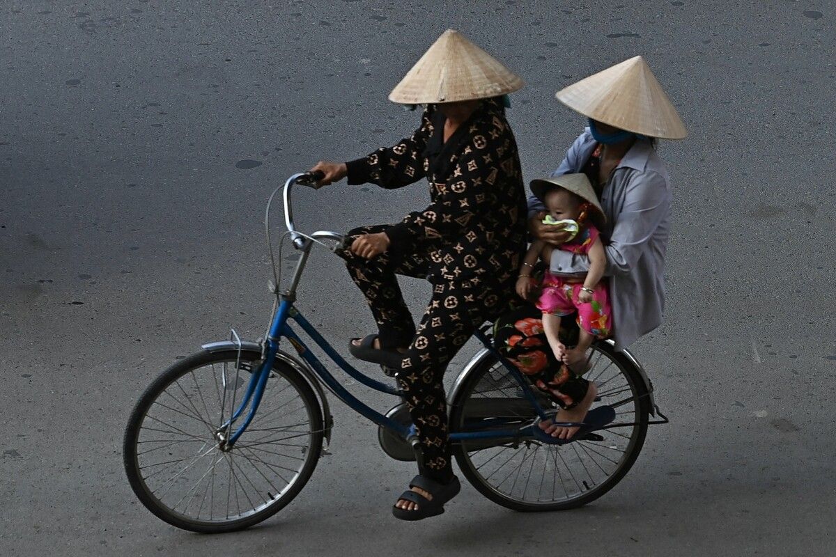 Eine Fahrradfahrerin transportiert in Can Tho City in Vietnam eine Frau und ein Baby auf dem Gepäckträger. AFP