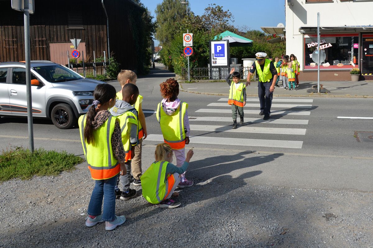 Stadtpolizisten zeigen den Kindern, wie sich beim Überqueren einer Straße auf sich aufmerksam machen.Stadt