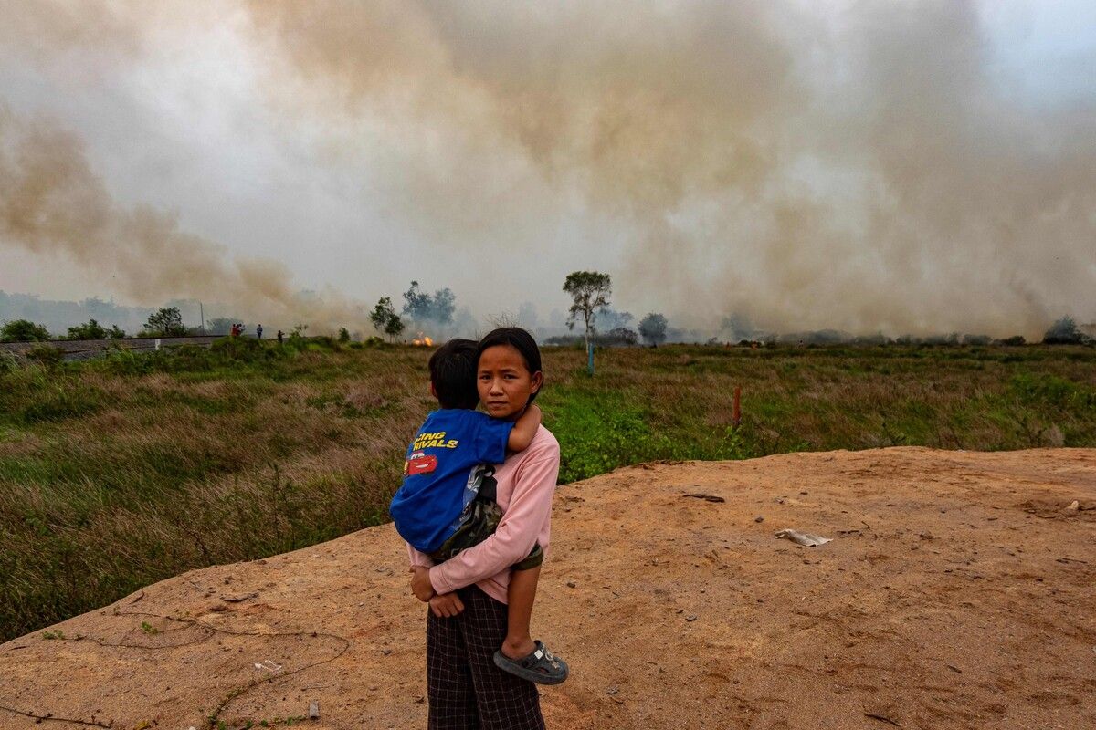 Während die Feuerwehr versucht, einen Torfbrand in der Nähe ihres Hauses in Palembang auf Sumatra zu löschen, hält ein Mädchen ihren kleinen Bruder im Arm. AFP