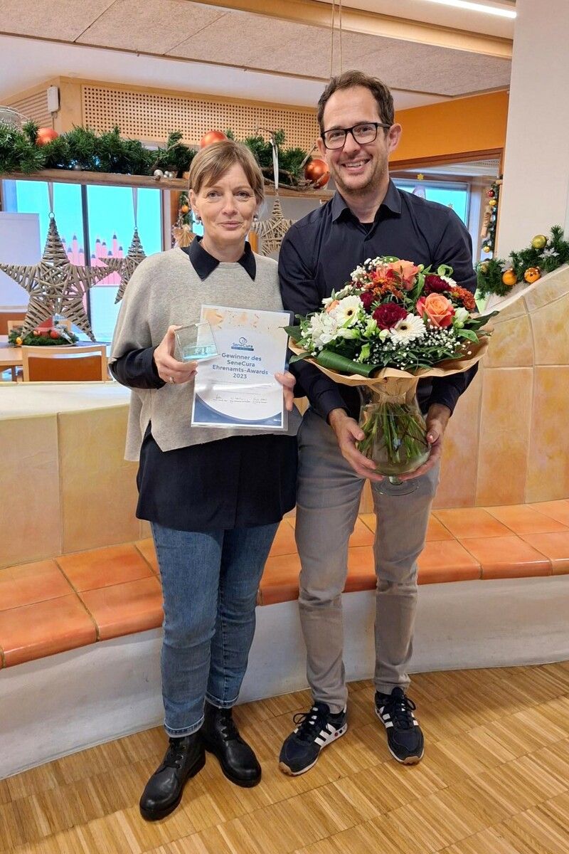 Auch die Ehrenamtliche Anni Amann darf sich über den Ehrenamts-Award freuen und bekommt von Hausleiter Alexander Welte noch einen Blumenstrauß.