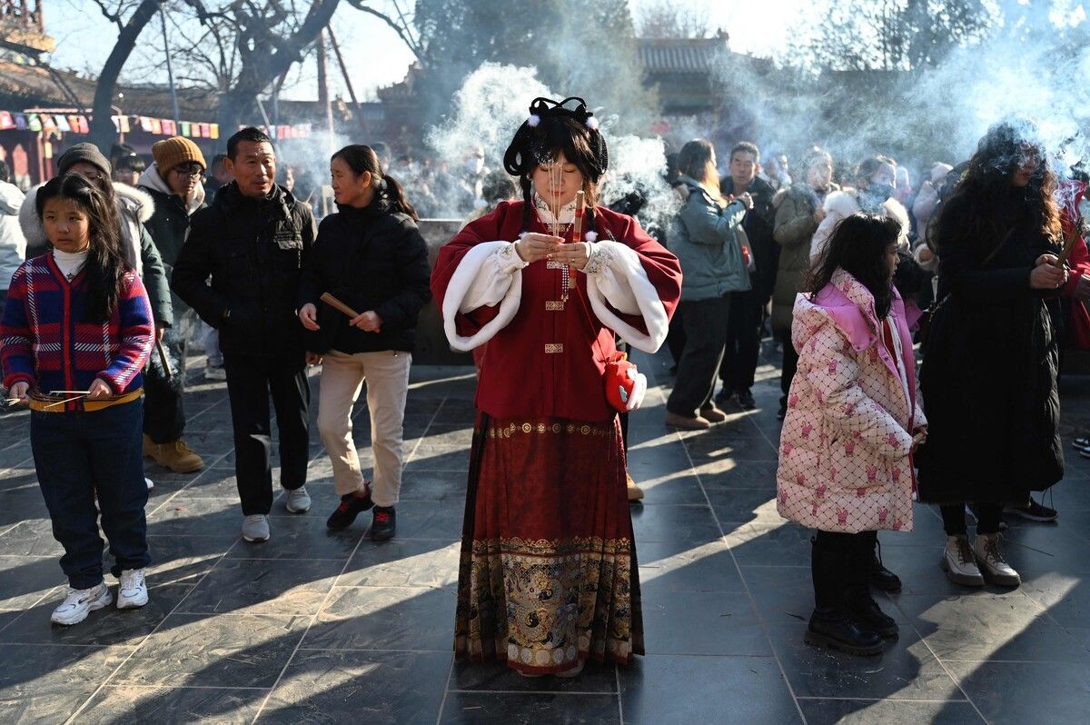 Eine Frau in traditioneller Kleidung betet im Lama-Tempel am ersten Tag des Mondneujahrs des Drachen in Peking in China. AFP