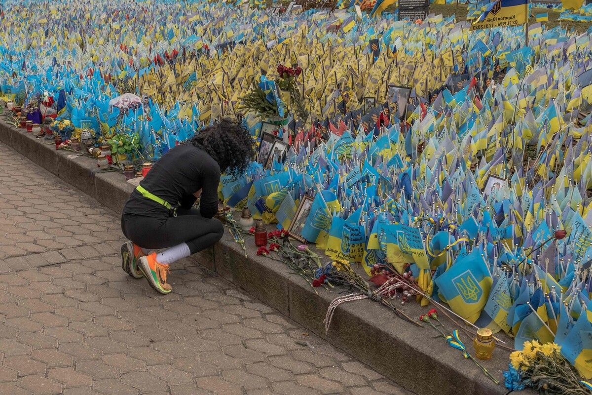 Eine Frau legt am zweiten Jahrestag der russischen Invasion auf dem Unabhängigkeitsplatz in Kiew Blumen nieder. AFP