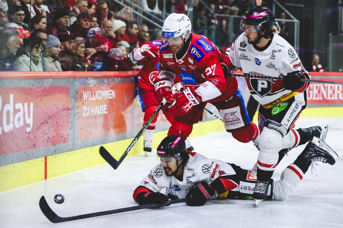 Clayton Kirichenko (liegend) und Nick Pastujov (r.) bearbeiten KAC-Kapitän Thomas Hundertpfund.Gepa