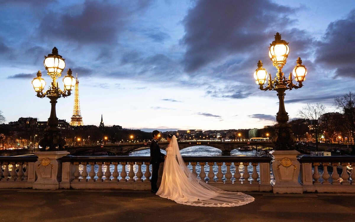 Ein frisch verheiratetes Paar posiert bei Sonnenuntergang für romantische Hochzeitsfotos auf der Pont Alexandre III an der Seine in Paris. AFP
