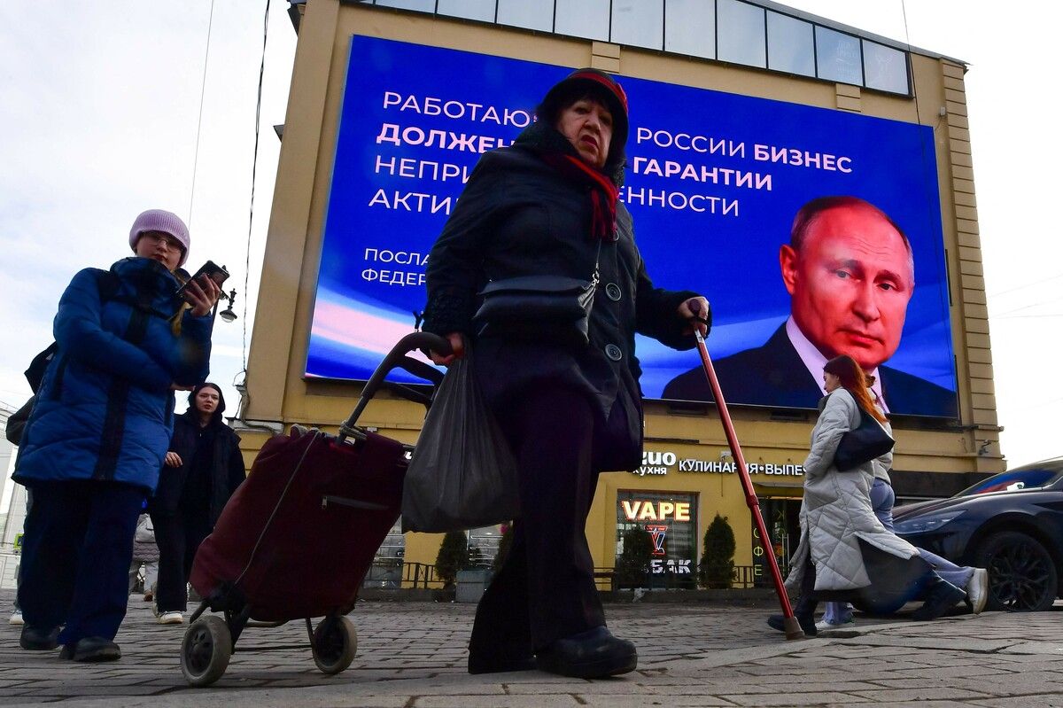 Menschen gehen an einem Plakat vorbei, auf dem Propaganda-Nachrichten des russischen Präsidenten Wladimir Putin zu sehen sind. AFP