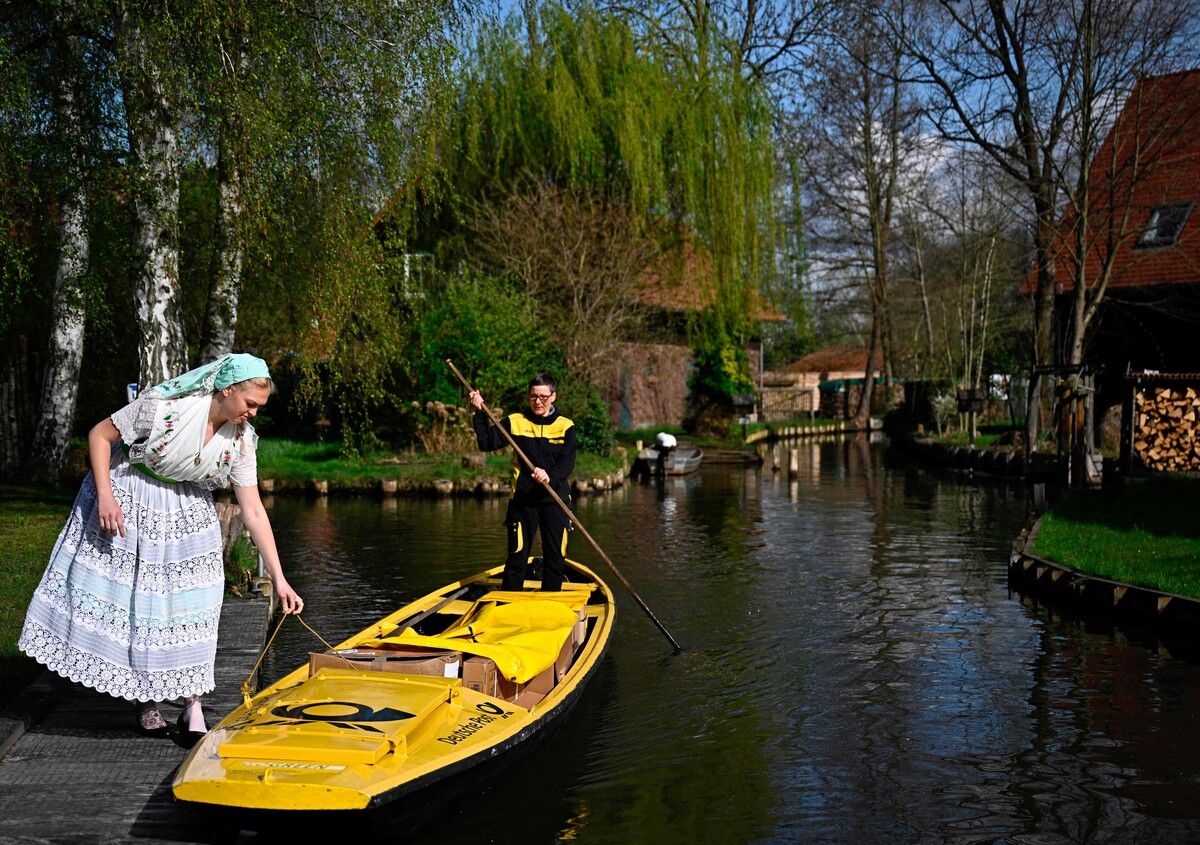 Die deutsche Postangestellte Andrea Bunar wird von einer ortsansässigen Frau in Tracht auf einem Kanal im Spreewaldgebiet unterstützt. AFP