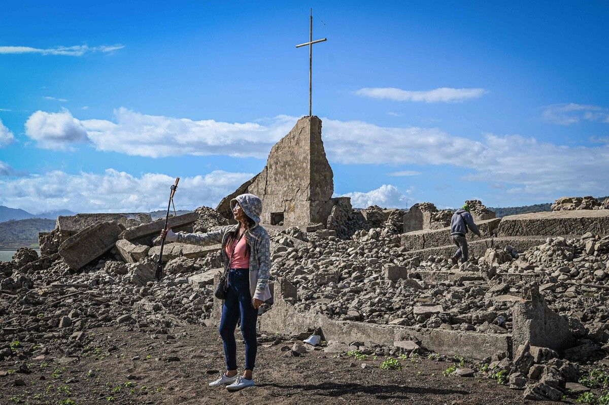 Vor den Ruinen einer Kirche in der wieder freigelegten, eigentlich versunkenen alten Stadt Pantabangan auf den Philippinen macht eine Frau ein Foto. AFP