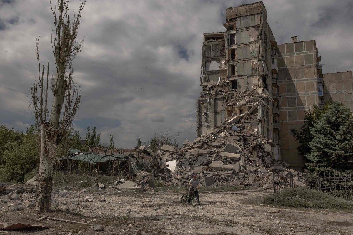 Ein Mann schiebt sein Fahrrad an einem zerstörten Haus vorbei, nachdem die Stadt Torezk in der Ostukraine von Russland beschossen wurde. AFP