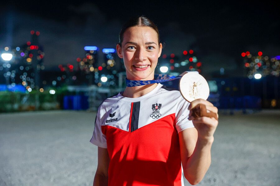 Bettina Plank vor der Skyline von Tokio mit ihrer Olympiamedaille.GEpa (29, Grafoner