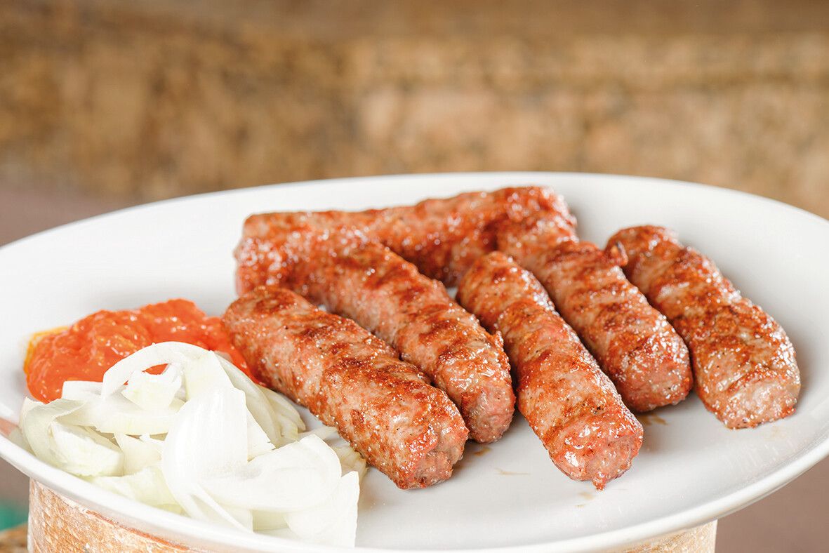 Cevapcici werden in Serbien gerne mit Zwiebeln und Ajvar serviert.Shutterstock