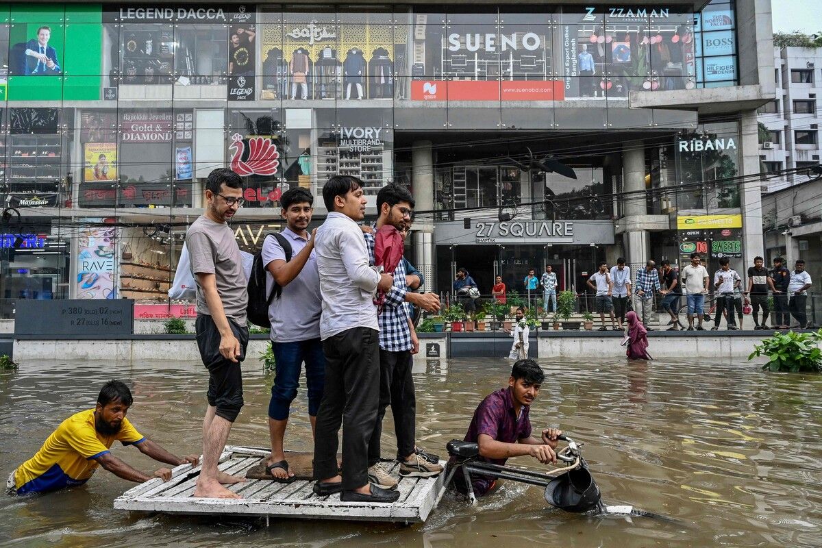 Menschen stehen auf dem Dach eines Transportfahrrads, während Bangladeschs Hauptstadt Dhaka nach Regenfällen überschwemmt ist. AFP