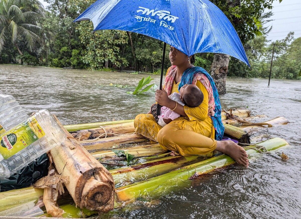 Eine Frau und ihr Kind treiben in Feni durch die Fluten. Durch sintflutartige Regenfälle wurden Teile Bangladeschs überschwemmt. AFP