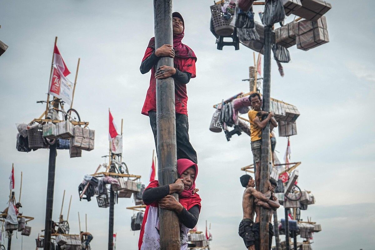 Frauen klettern in Sumatra, in Indonesien, auf einen vier Meter hohen, mit Öl bestrichenen Baumstamm, um an der Spitze Preise zu sammeln. AFP