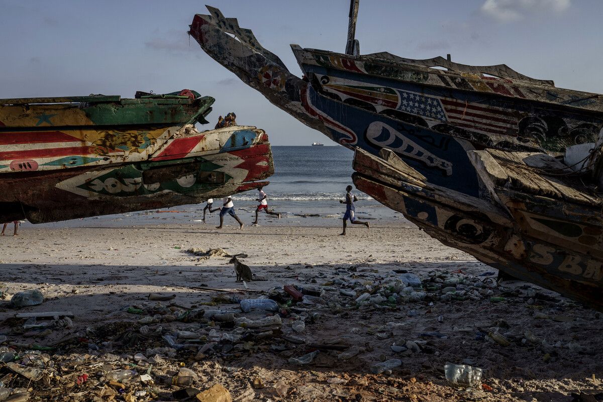 Kinder spielen am Strand von Senegal. Vorne stehen Fischerboote, mit denen jährlich Tausende Migranten ihre riskante Reise antreten. AFP