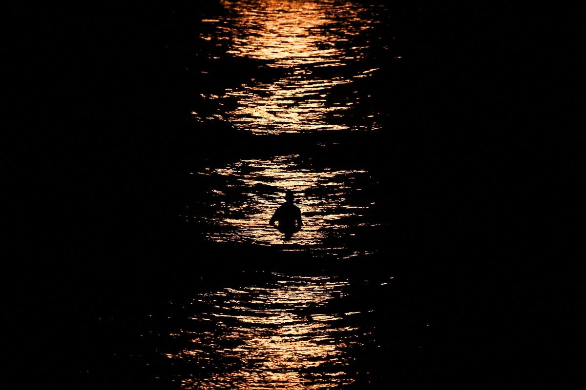 Ein Surfer wird, während er auf seinem Brett sitzt, von einem Supermond beleuchtet, der am Manly Beach in Sydney aufgeht. AFP