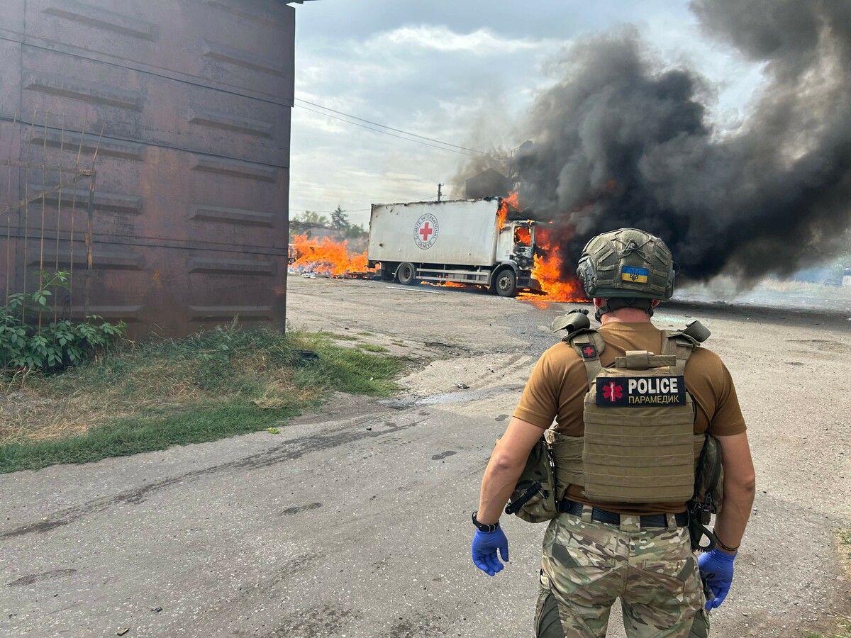 Ein ukrainischer Polizist betrachtet den nach einem russischen Beschuss brennenden Lkw des Roten Kreuzes in Donezk. ⇒AFP