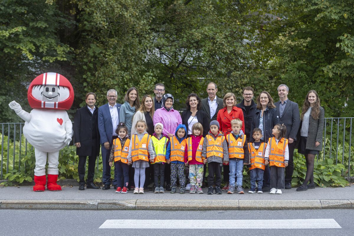 Martin Pfanner (KFV, v.l.), Robert Sturn (VLV), Andreas Neuhauser (illwerke vkw), Mario Amann (Sicheres Vorarlberg), Landesrätin Barbara Schöbi-Fink, Lucas Hepberger (VN), Angelika Walser (Bildungsdirektion), Michael Thaler (Stadt Dornbirn), Mirijam Haller (VN) und das Team des Kindergartens Am Wall bei der Warnwesten-Übergabe an die Kleinen.⇒VN/Paulitsch