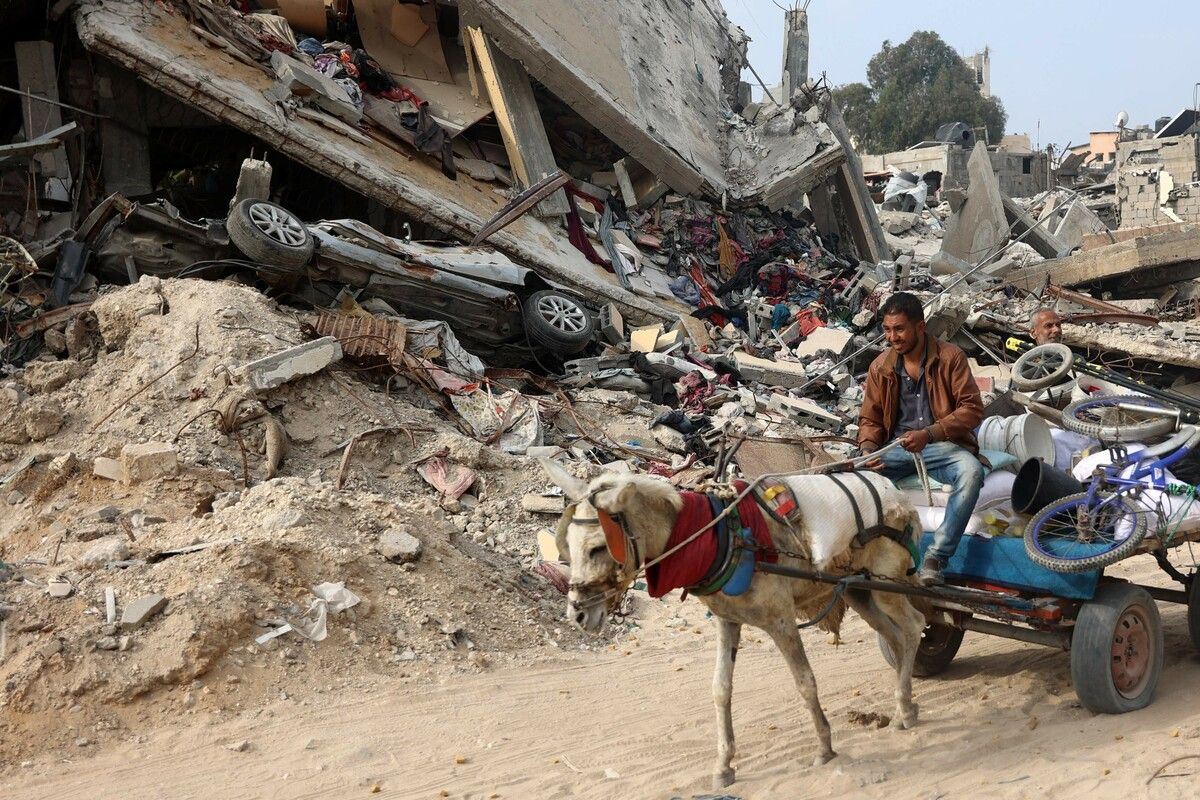 Ein Palästinenser fährt in Gaza-Stadt mit seinen Habseligkeiten auf einem Pferdefuhrwerk neben einem völlig zerstörten Gebäude vorbei. AFP
