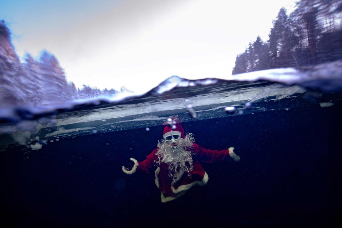 Der finnische Freitaucher Kristian Maki-Jussila schwimmt verkleidet als Weihnachtsmann unter dem Eis eines zugefrorenen Sees in Finnland. AFP