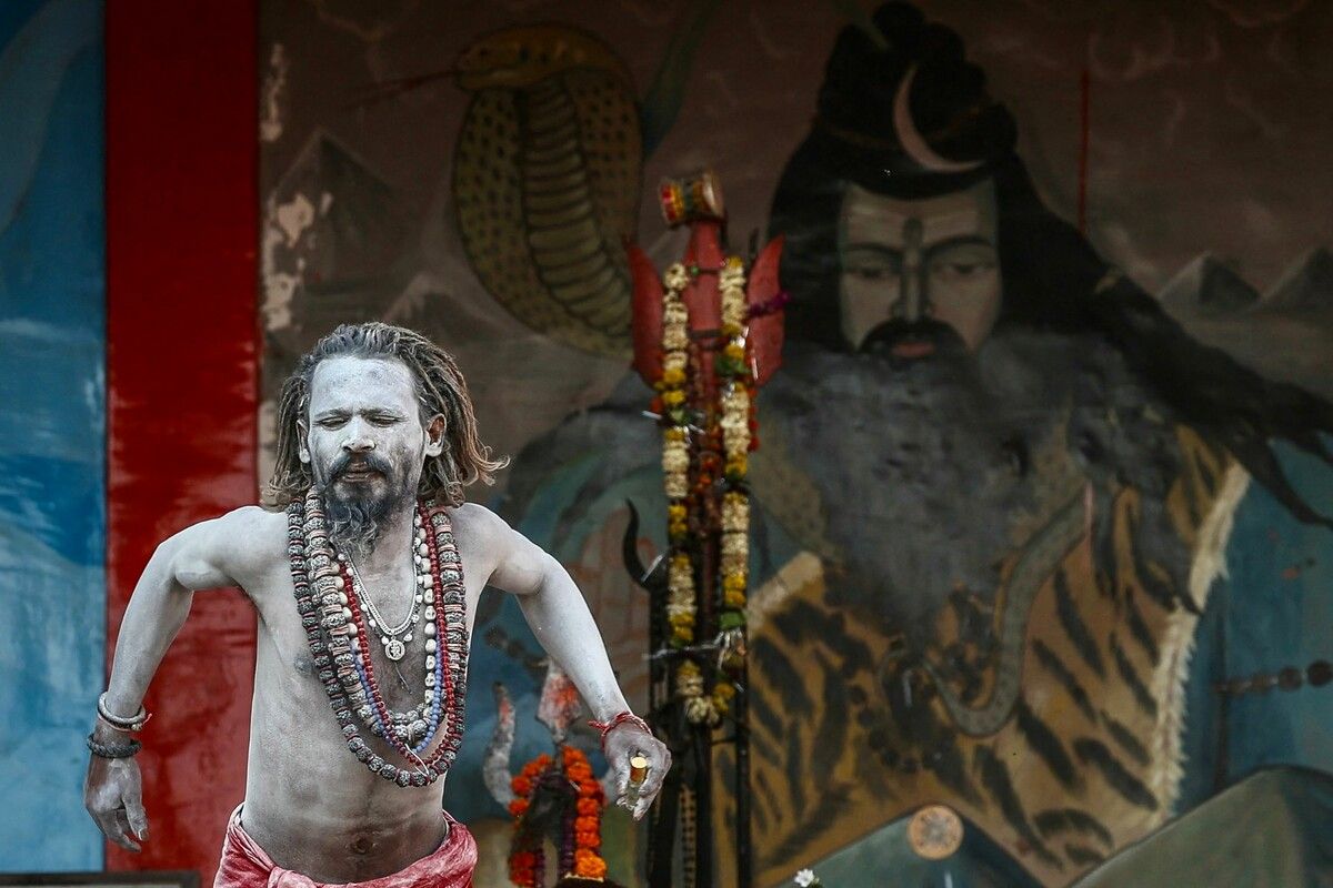 Ein mit Asche bedeckter Priester vor einem Wandgemälde des Hindu-Gottes Shiva am Dashashwamedh Ghat in Varanasiie. AFP