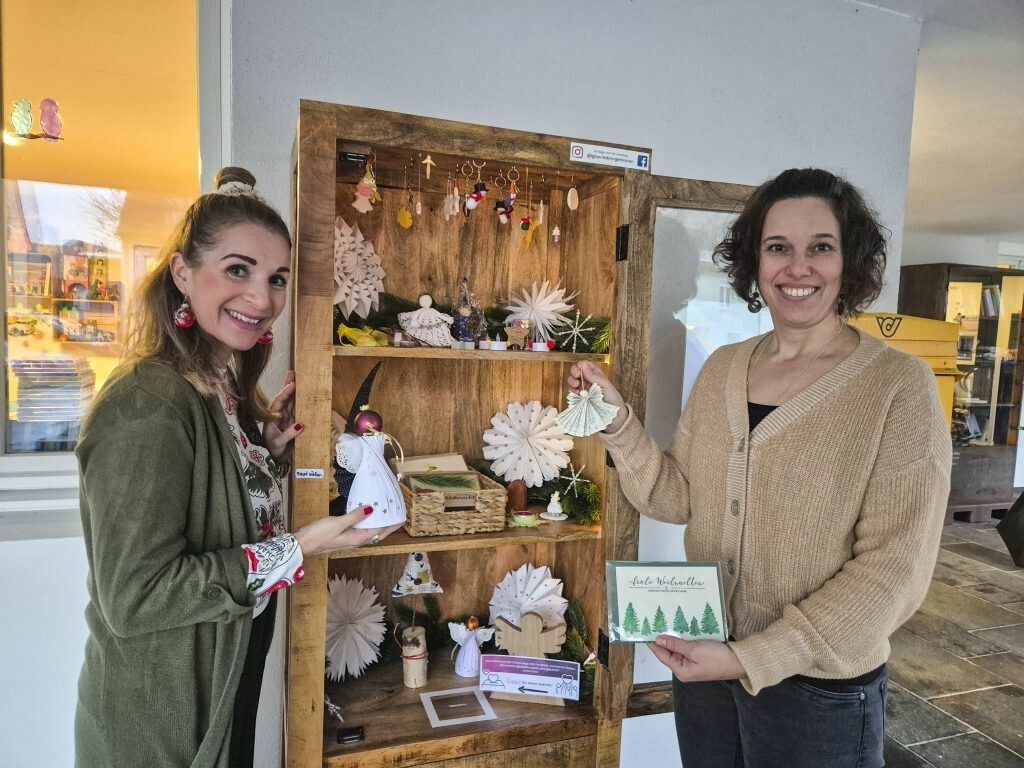 Stefanie Maier (l.) und Martina Jussel (r.) befüllen täglich den Glücksbringerkasten, der vor ihrem Kinderlädile auf dem Dorfplatz in Bürs steht. ⇒VN/JUN