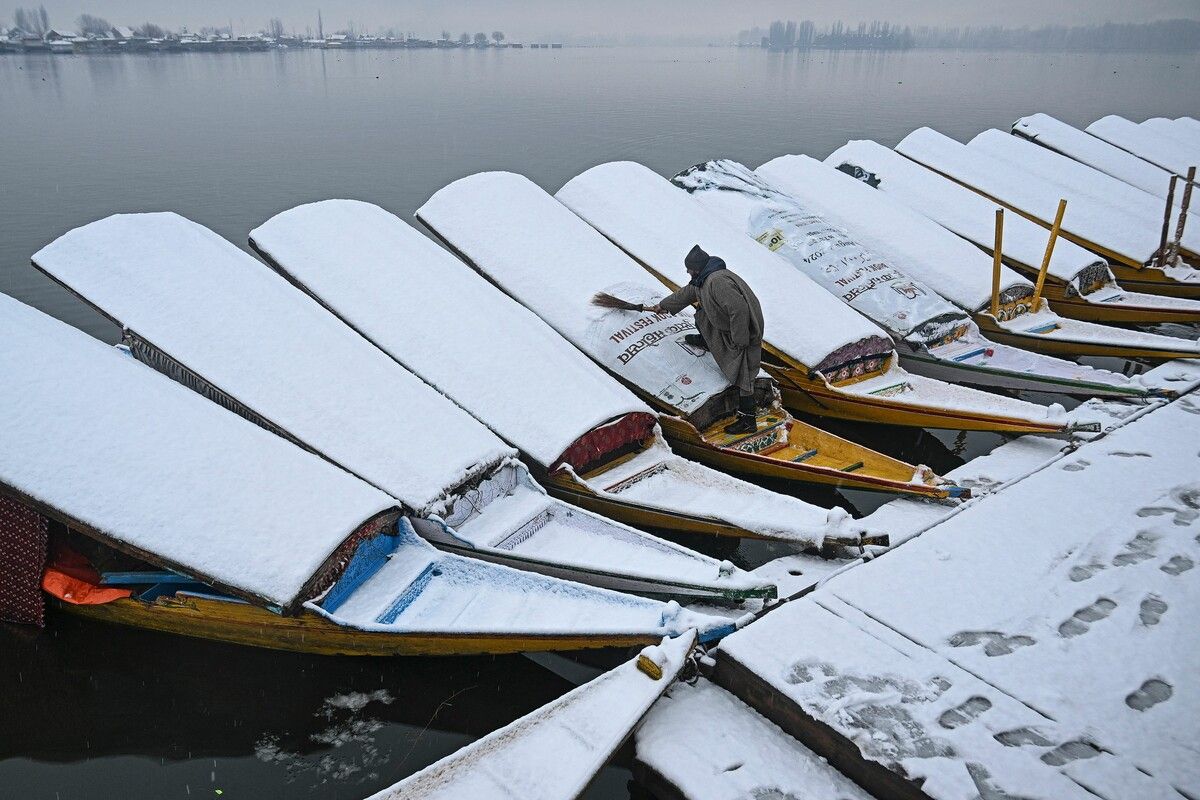 Ein Bootsmann reinigt schneebedeckte Boote in der Nähe des Dal-Sees, nachdem in Srinagar Neuschnee gefallen ist. AFP