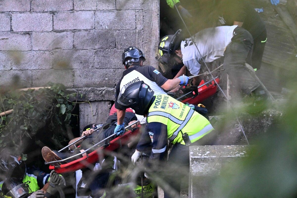 Feuerwehrleute und Polizisten transportieren Verunglückte ab. ⇒afp