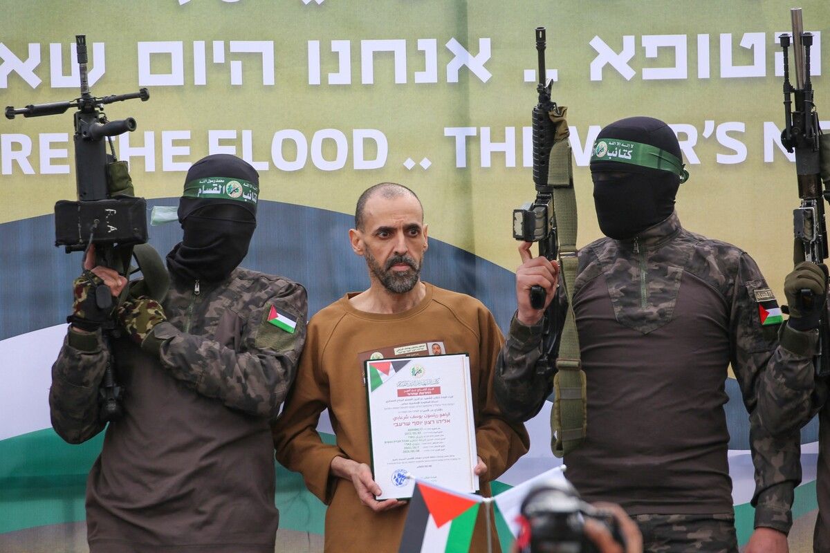 Hamas-Kämpfer eskortieren die israelische Geisel Eli Sharabi auf eine Bühne, bevor sie ihn an das Rote Kreuz übergeben.⇒AFP