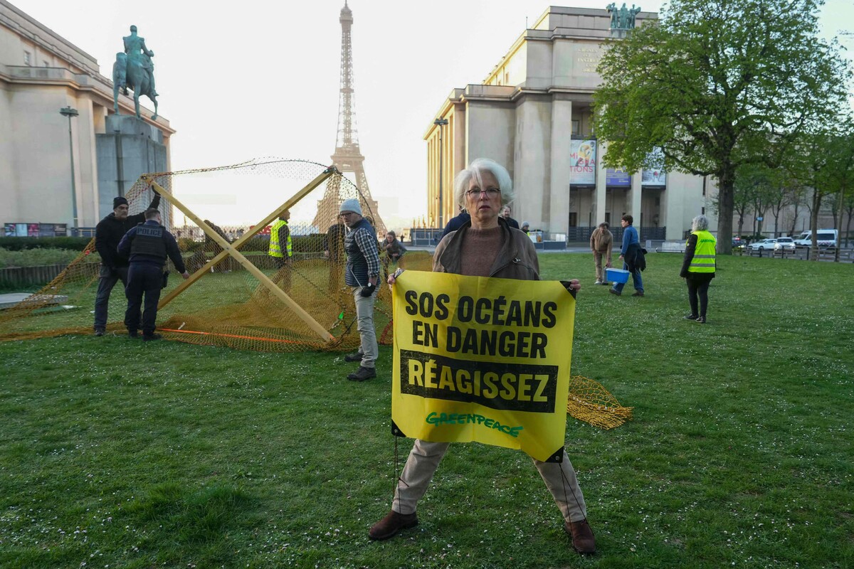Eine Greenpeace-Aktivistin hält ein Transparent mit der Aufschrift „SOS, Ozeane in Gefahr, reagiert“ auf dem Place du Trocadero in Paris.