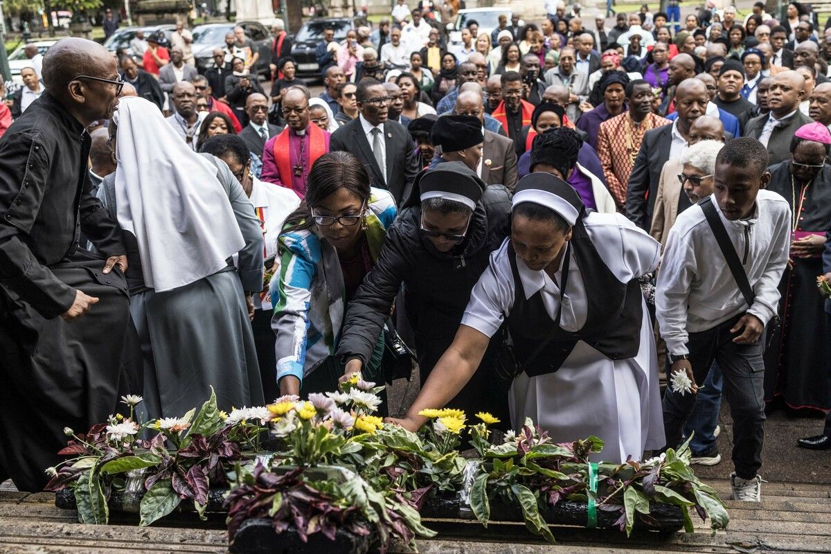 Christen legen während einer Karfreitagsprozession auf den Stufen des Rathauses von Durban Blumen nieder.