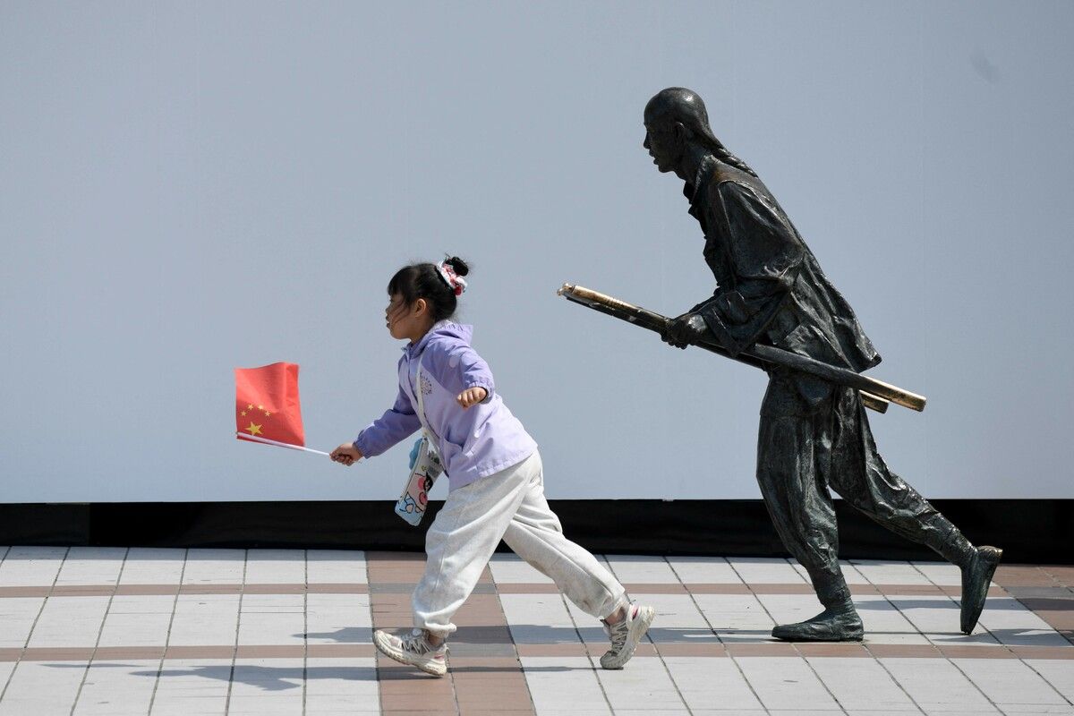 Ein Kind mit der chinesischen Nationalflagge läuft in der Hauptstadt Peking an einer Bronzestatue vorbei. AFP (4)