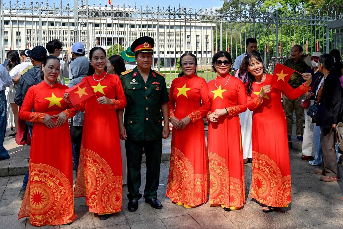 Ein vietnamesischer Veteran posiert vor dem Unabhängigkeitspalast mit Frauen in Ao-Dai-Kleidern vor den Feiern zum 50. Jahrestag des Nordvietnamsiegs.