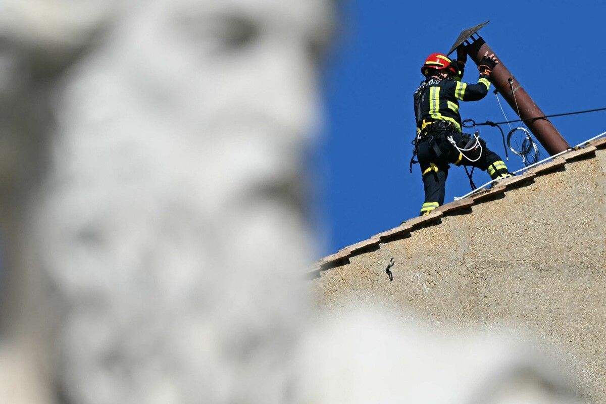 Ein Feuerwehrteam installierte das rund zwei Meter lange Rohr auf dem Dach der Sixtinischen Kapelle, durch das nach den Wahlgängen der Rauch der verbrannten Stimmzettel entweicht. ⇒AFP