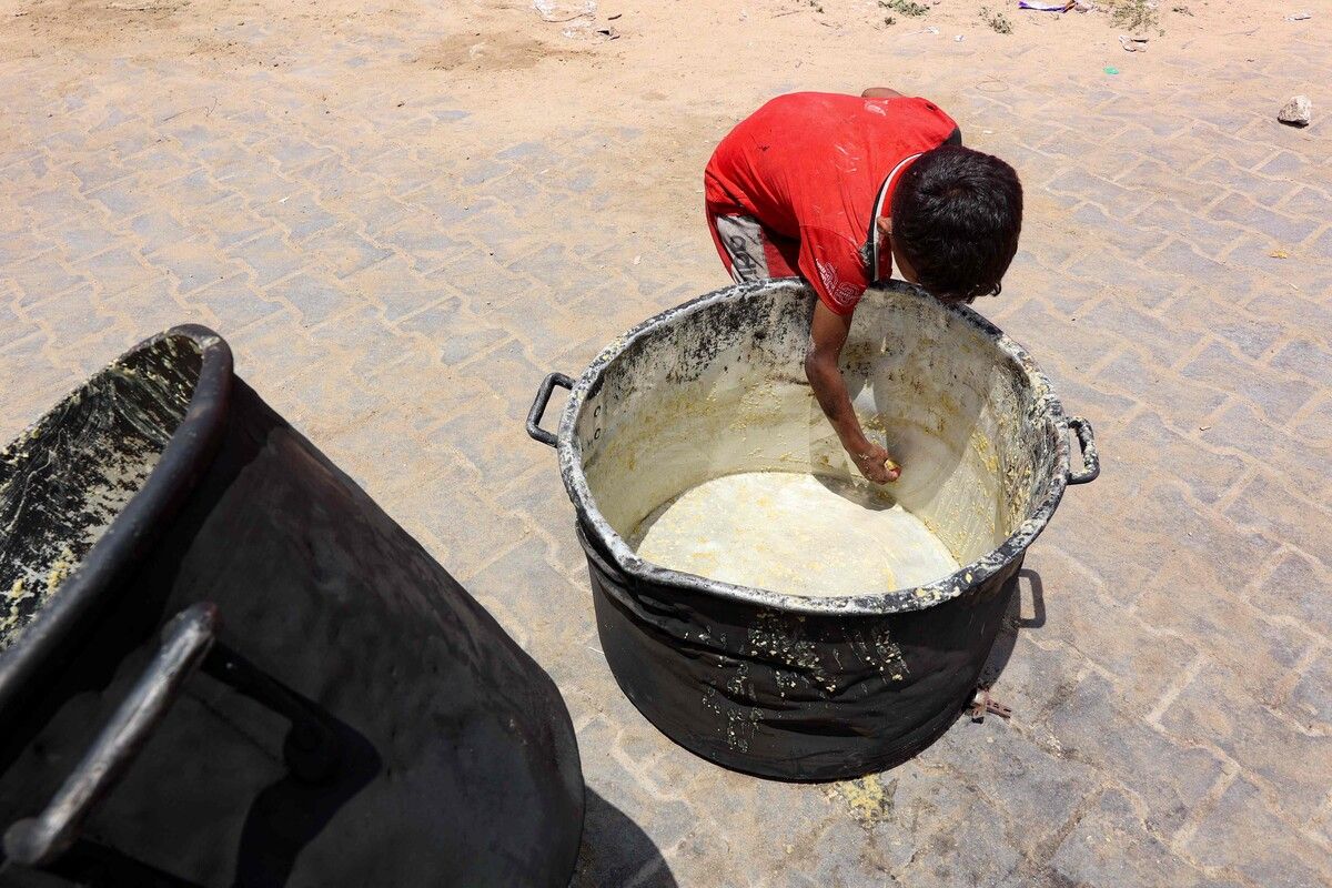Ein palästinensischer Junge kratzt die Reste einer Linsensuppe aus einem Kochtopf in Gaza.
