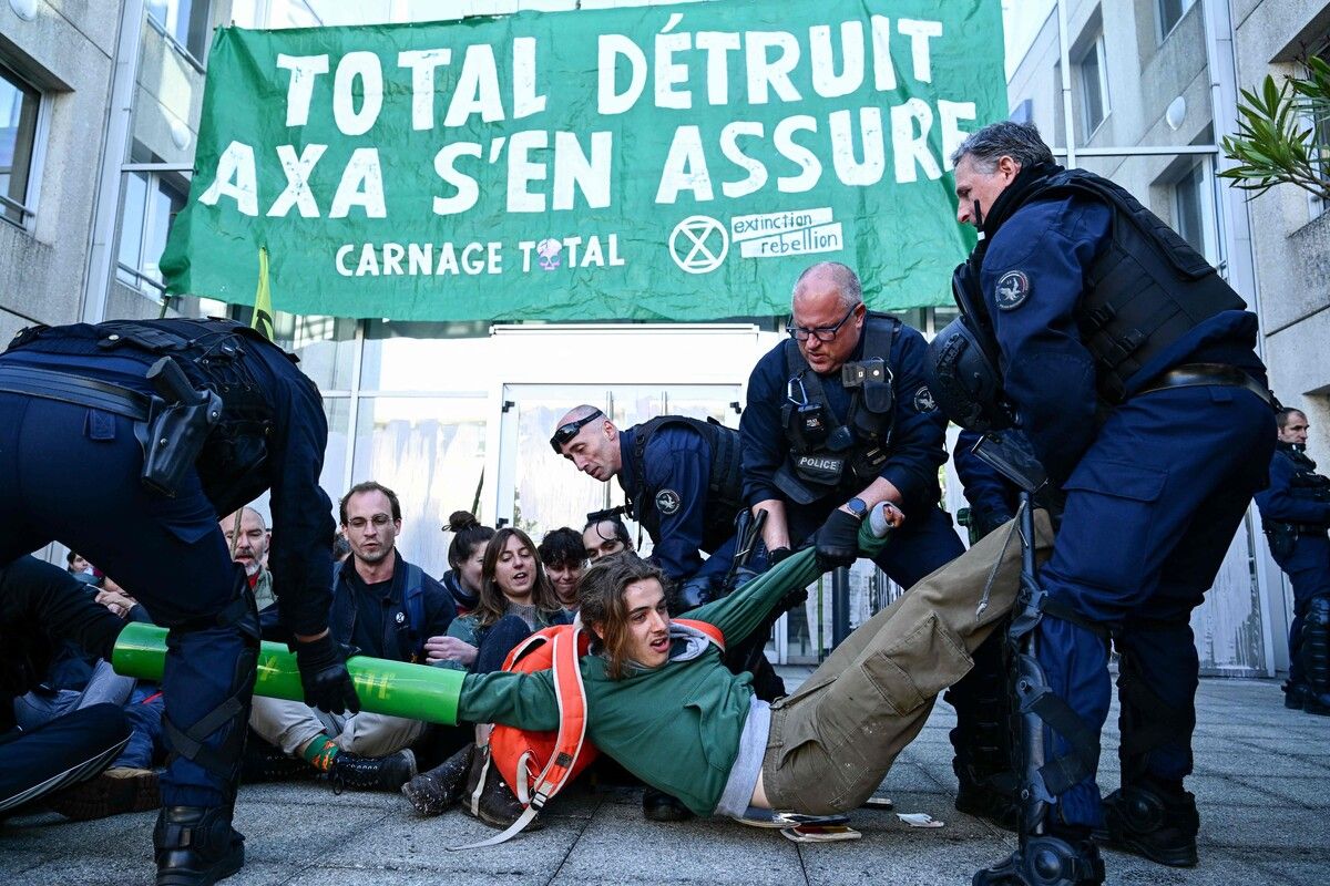 Klimaaktivisten der Gruppe Extinction Rebellion werden vor dem französischen Versicherungsunternehmens AXA in Nantes von Polizisten festgehalten.