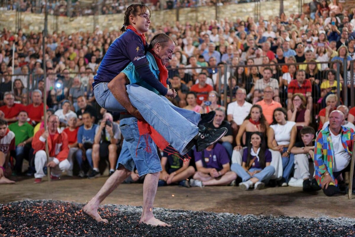 Feuerlauf zum San-Juan-Fest in San Pedro Manrique in Spanien: Ein Mann trägt ein Mädchen barfuß über glühende Kohlen.