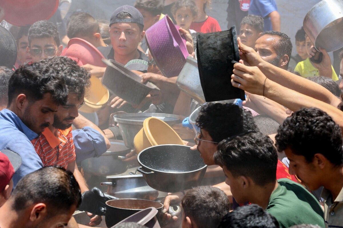 Palästinenser versuchen in einer Wohltätigkeitsküche in Gaza-Stadt, die warme Mahlzeiten anbietet, Lebensmittel zu ergattern.